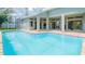 Back view of house featuring a screened-in in-ground pool and patio at 1647 Stable Trl, Palm Harbor, FL 34685