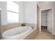 An oval tub with jets, complemented by a window and a walk-in closet in this bathroom at 7327 Brightwaters Ct, New Port Richey, FL 34652