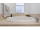 A pristine white oval bathtub beneath a window for natural light in a tiled bathroom at 7327 Brightwaters Ct, New Port Richey, FL 34652