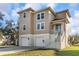 Two-story beige home featuring white trim, multi-car garage, and staircase leading to the front door at 7327 Brightwaters Ct, New Port Richey, FL 34652