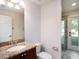 Bathroom with granite countertop vanity, toilet, and a door to an outdoor patio at 12402 Creek Edge Dr, Riverview, FL 33579