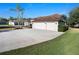 Long driveway leads to a three car garage on this single-story home, showcasing lush landscaping and mature trees at 12402 Creek Edge Dr, Riverview, FL 33579