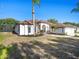 Side view of the single-story home, highlighting stucco siding, screened-in porch, manicured lawn and tropical landscaping at 12402 Creek Edge Dr, Riverview, FL 33579