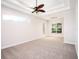 Empty main bedroom featuring tray ceilings, a ceiling fan, and ample natural light at 12402 Creek Edge Dr, Riverview, FL 33579