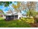 A beautiful outdoor view of the home showing a screened porch, large grassy yard, and mature trees at 1610 Spinning Wheel Dr, Lutz, FL 33559