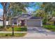 Charming single-story home with a well-manicured lawn, two-car garage, and a beautiful dark purple front door at 1610 Spinning Wheel Dr, Lutz, FL 33559