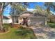 Charming single-story home with a well-manicured lawn, two-car garage, and a beautiful dark purple front door at 1610 Spinning Wheel Dr, Lutz, FL 33559