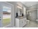 Bright bathroom with walk-in shower, white vanity, and outdoor access through louvered doors at 32554 Silvercreek Way, Wesley Chapel, FL 33545