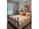 Inviting bedroom with a black metal bed frame, warm colored pillows, and a dresser with table lamps at 1427 Hyssop Loop, North Port, FL 34289