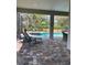 Covered lanai with brick pavers overlooks pool and spa with tropical landscaping at 1427 Hyssop Loop, North Port, FL 34289
