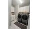 Well-lit laundry room with gray washer and dryer, white cabinets, and a gray rug at 1427 Hyssop Loop, North Port, FL 34289