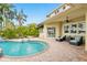 Patio view of a backyard pool with rock waterfall, lush palm trees, and cozy seating area at 5405 Merritt Island Dr, Apollo Beach, FL 33572