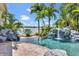 Backyard pool with rock features and waterfall, surrounded by lush palm trees and serene water views at 5405 Merritt Island Dr, Apollo Beach, FL 33572