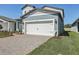 Attached two-car garage with white door, brick accents and a paver driveway at 1869 Brekey Way, Zephyrhills, FL 33541