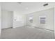 Open living room featuring neutral carpeting, access to the staircase, and two windows for natural light at 1869 Brekey Way, Zephyrhills, FL 33541