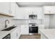 Close-up of a kitchen showcasing white cabinets, herringbone backsplash, stainless steel appliances, and quartz countertops at 7272 Deer Valley Circle, Tampa, FL 33635