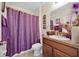 Cozy bathroom with a vanity, toilet, shower with decorative purple curtain, and elegant decor at 10607 Standing Stone Drive, Wimauma, FL 33598