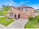 Charming two-story home with a well-maintained lawn, tall palm tree and attached two car garage at 10607 Standing Stone Drive, Wimauma, FL 33598