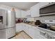 Compact kitchen featuring stainless steel refrigerator, and white cabinets with laminate countertops at 215 Melody Ln, Largo, FL 33771