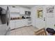 Functional kitchen with white cabinetry, tile floors, and an access door to the outside at 215 Melody Ln, Largo, FL 33771