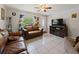 Cozy living room featuring tile flooring, comfortable leather sofas, and a ceiling fan at 215 Melody Ln, Largo, FL 33771