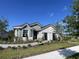 Inviting single-story home showcasing stone details, gray siding, lush landscaping, and a well-manicured front yard at 2718 Wise River Lane, Zephyrhills, FL 33539