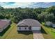 Aerial view of single-Gathering home with a two-car garage, neutral color palette, and surrounded by mature trees at 80 Sequoyah Dr, Port Charlotte, FL 33954