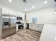Modern kitchen featuring stainless steel appliances, white cabinetry, stone countertops, and wood grain floors at 80 Sequoyah Dr, Port Charlotte, FL 33954