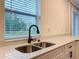 Stainless steel kitchen sink under a window with white cabinets and quartz countertops at 80 Sequoyah Dr, Port Charlotte, FL 33954