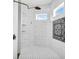 Modern shower featuring sleek fixtures, white brick-style walls, and stylish black and white tile accents at 6306 Foxbrook Trl, Parrish, FL 34219
