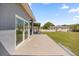 View of tiled back patio, sliding glass doors, and manicured lawn at 16805 Tobacco Rd, Lutz, FL 33558