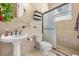 Classic bathroom features a pedestal sink, toilet, and a glass-enclosed shower with marble-style walls at 16805 Tobacco Rd, Lutz, FL 33558
