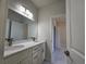 Bathroom boasts double vanity with white cabinets and quartz countertops; tile floor extends to bedroom entry at 3105 Lockwood St, Port Charlotte, FL 33952