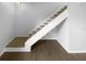 A well-lit staircase featuring carpeted steps, a white handrail, and wood-look flooring at the base at 1857 Clearbrooke Dr, Clearwater, FL 33760