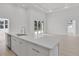 Modern kitchen island with white cabinets, stainless steel sink, and views of the adjacent living area at 2551 Alhaven Ter, North Port, FL 34286