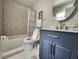 Stylish bathroom featuring a blue vanity with modern fixtures, a shower with decorative tiling and a round mirror at 2806 W Shelton Ave, Tampa, FL 33611
