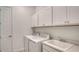 Bright laundry room with white cabinets, washer, dryer, and utility sink at 18213 Cresswind Ter, Lakewood Ranch, FL 34211