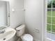 Bright bathroom featuring a white sink, toilet, and a view of the backyard at 2007 Rain Dance Pl, Brandon, FL 33510