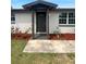 Inviting front entrance with a gray door, well-manicured landscaping, and a welcoming pathway at 3213 Bigelow Dr, Holiday, FL 34691