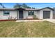 Charming single-story home featuring a gray door, attached garage, manicured lawn, and well maintained landscaping at 3213 Bigelow Dr, Holiday, FL 34691