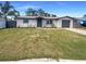 Charming single-story home with a well-maintained lawn, a gray door, and a one car garage at 3213 Bigelow Dr, Holiday, FL 34691