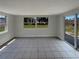 Bright empty living room with large windows, tile floors, and a sliding glass door to the outside at 3213 Bigelow Dr, Holiday, FL 34691