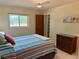 Cozy bedroom showcasing bright bedding, ceiling fan, dresser, and a window with a scenic view at 3652 Oak Grove Dr, Sarasota, FL 34243