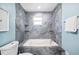 A luxurious bath with a tub encased in gray stone tile and featuring built in shelves at 8704 Bay Crest Ln, Tampa, FL 33615