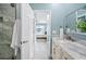 Ensuite bathroom with double vanity, marble countertop, and walk-in shower; view to bedroom at 8704 Bay Crest Ln, Tampa, FL 33615