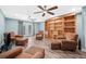 Open living room with wood floors, ceiling fans, built-in bookshelf, and comfortable leather seating at 8704 Bay Crest Ln, Tampa, FL 33615
