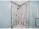 Walk-in shower featuring stylish stone-look tile and frameless glass enclosure at 8704 Bay Crest Ln, Tampa, FL 33615