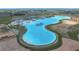 Aerial view of a community with a large blue lake, beach area, and water park at 10549 Torchwood Sea Way, San Antonio, FL 33576