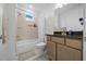 Bright bathroom with a shower-tub combo, granite countertop vanity, and neutral-toned tiles at 10549 Torchwood Sea Way, San Antonio, FL 33576