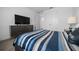 Bedroom with a large television, a dresser and a bed with striped bedding and a decorative pillow at 10549 Torchwood Sea Way, San Antonio, FL 33576